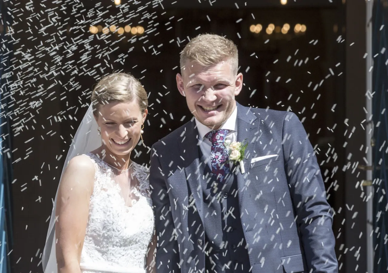 Glad nygift par går ud af kirken imens der kastes ris på dem