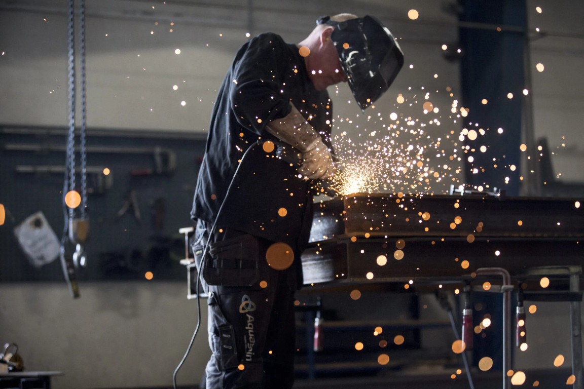 Mand står i værksted og svejer